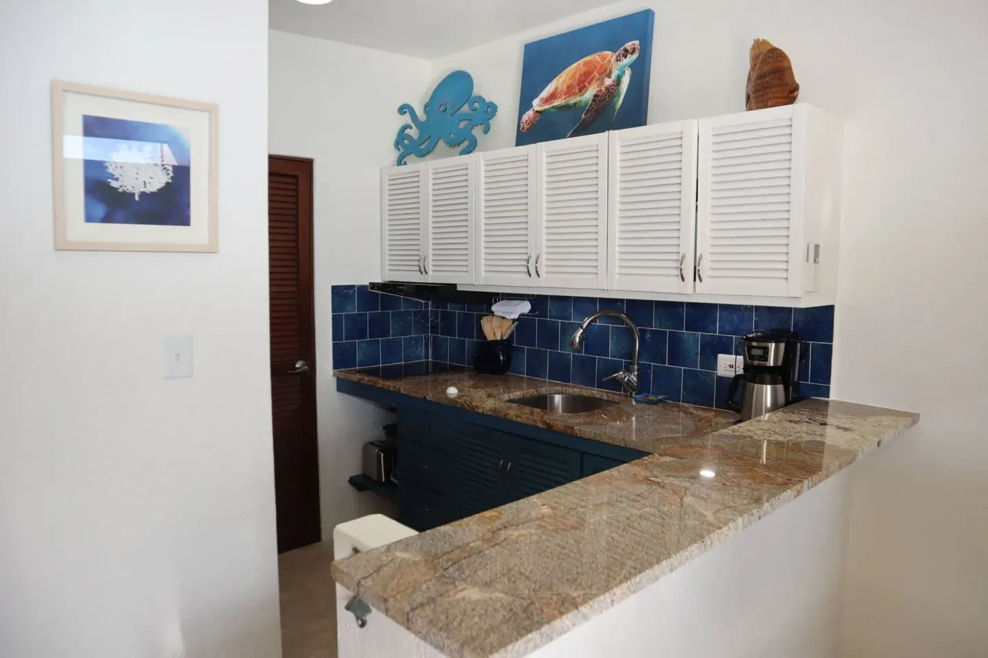 Kitchenette with blue tile backsplash and white cabinets at Point Pleasant Resort.