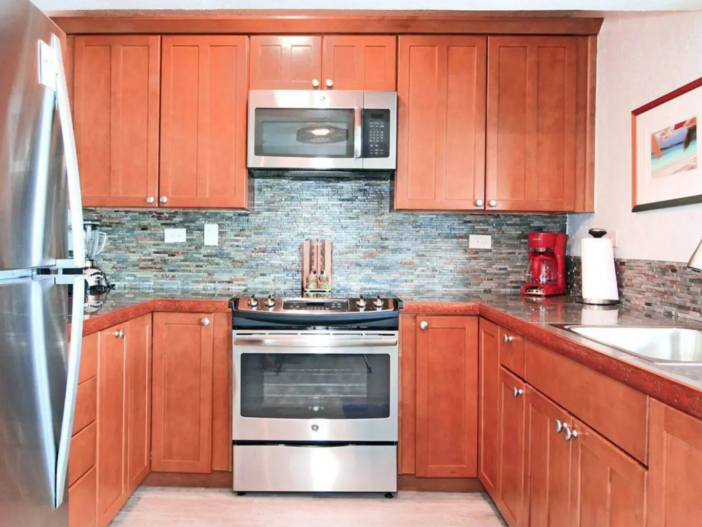 Wood cabinet kitchen with range, microwave and red coffee maker at Point Pleasant Resort.