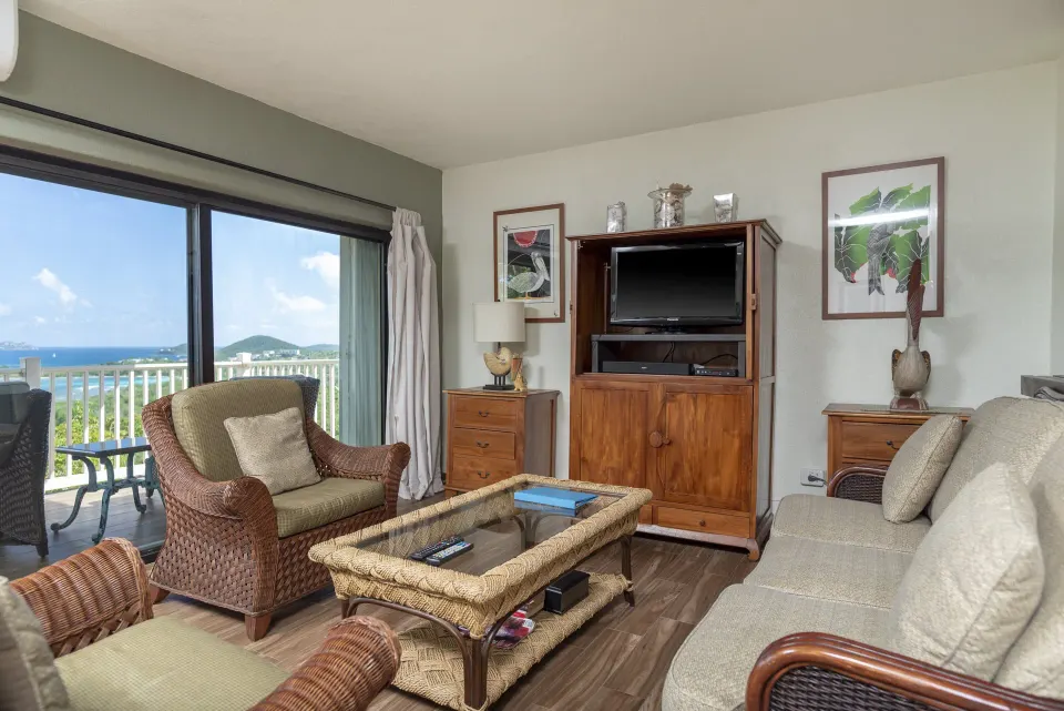 Condo living room with wicker chairs, sofa, and balcony view at Point Pleasant Resort.