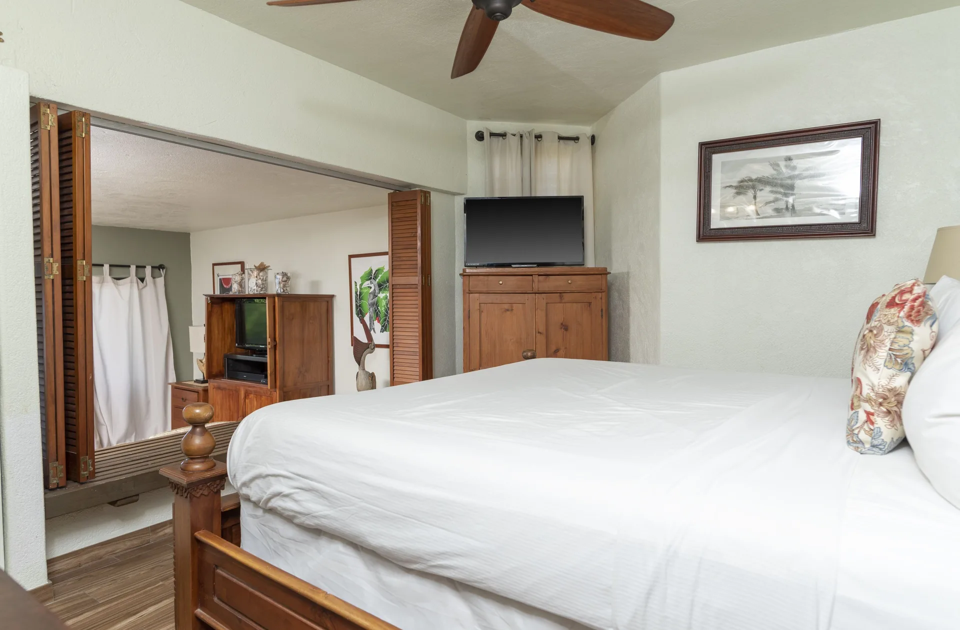 One-bedroom condo bedroom with white bed and wood furnishings at Point Pleasant Resort.