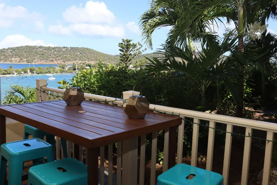 Studio balcony bar table with turquoise stools, palms, and water view at Point Pleasant Resort.