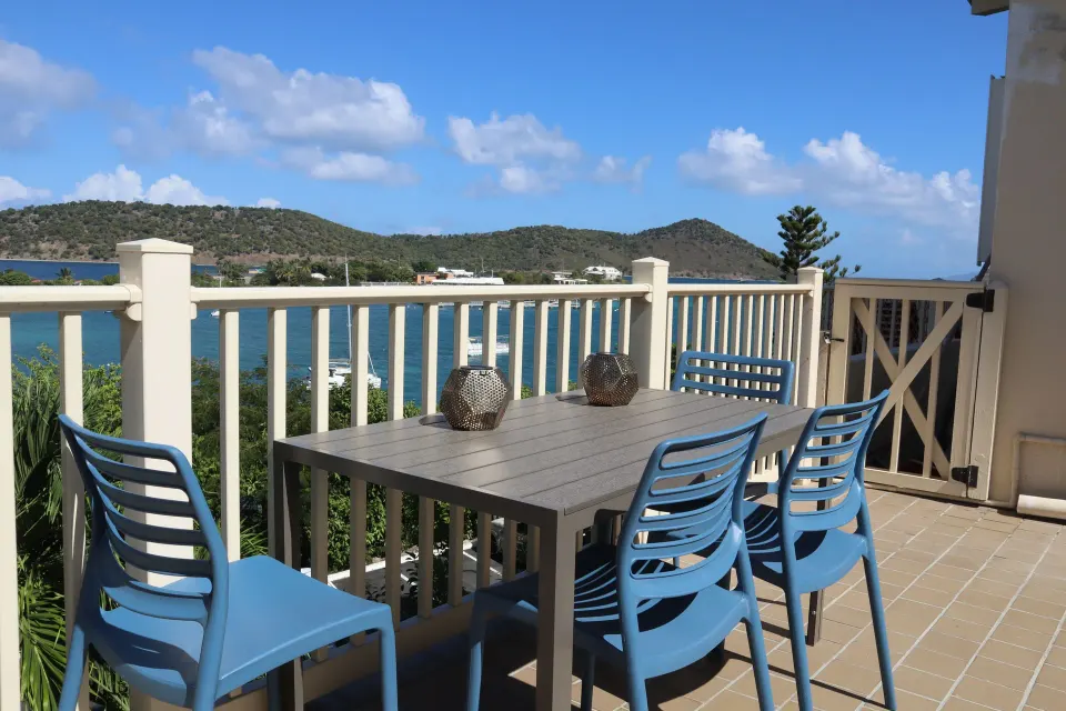 Studio balcony dining area with blue chairs and bay views at Point Pleasant Resort.