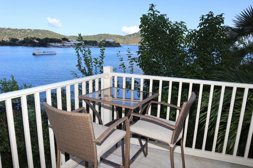 Studio balcony with table, two chairs, railing, and bay view at Point Pleasant Resort.