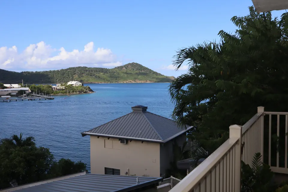 Studio balcony view of blue water, hillside, rooftops, and railing at Point Pleasant Resort.