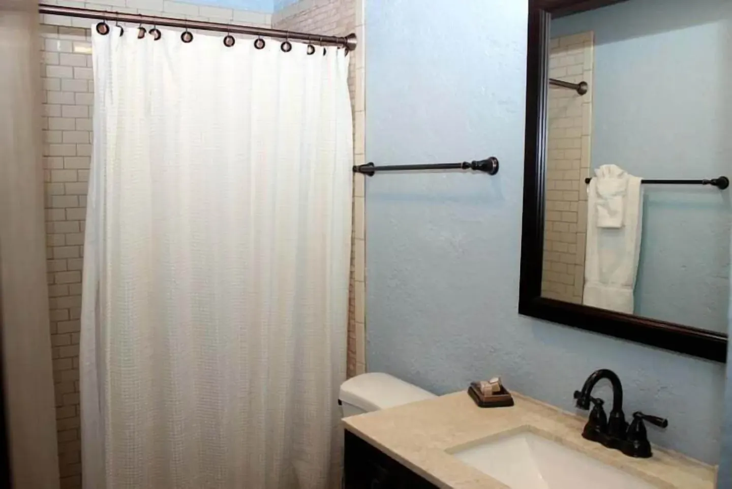 Studio bathroom with shower curtain and vanity sink at Point Pleasant Resort.