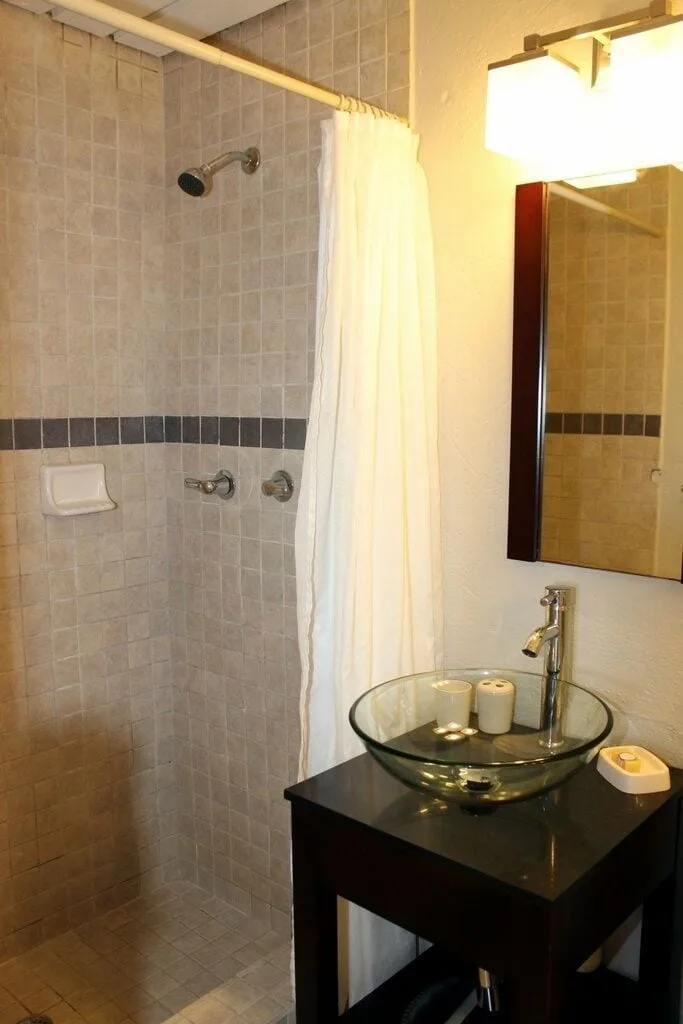 Studio bathroom at Point Pleasant Resort with tiled shower and glass vessel sink.