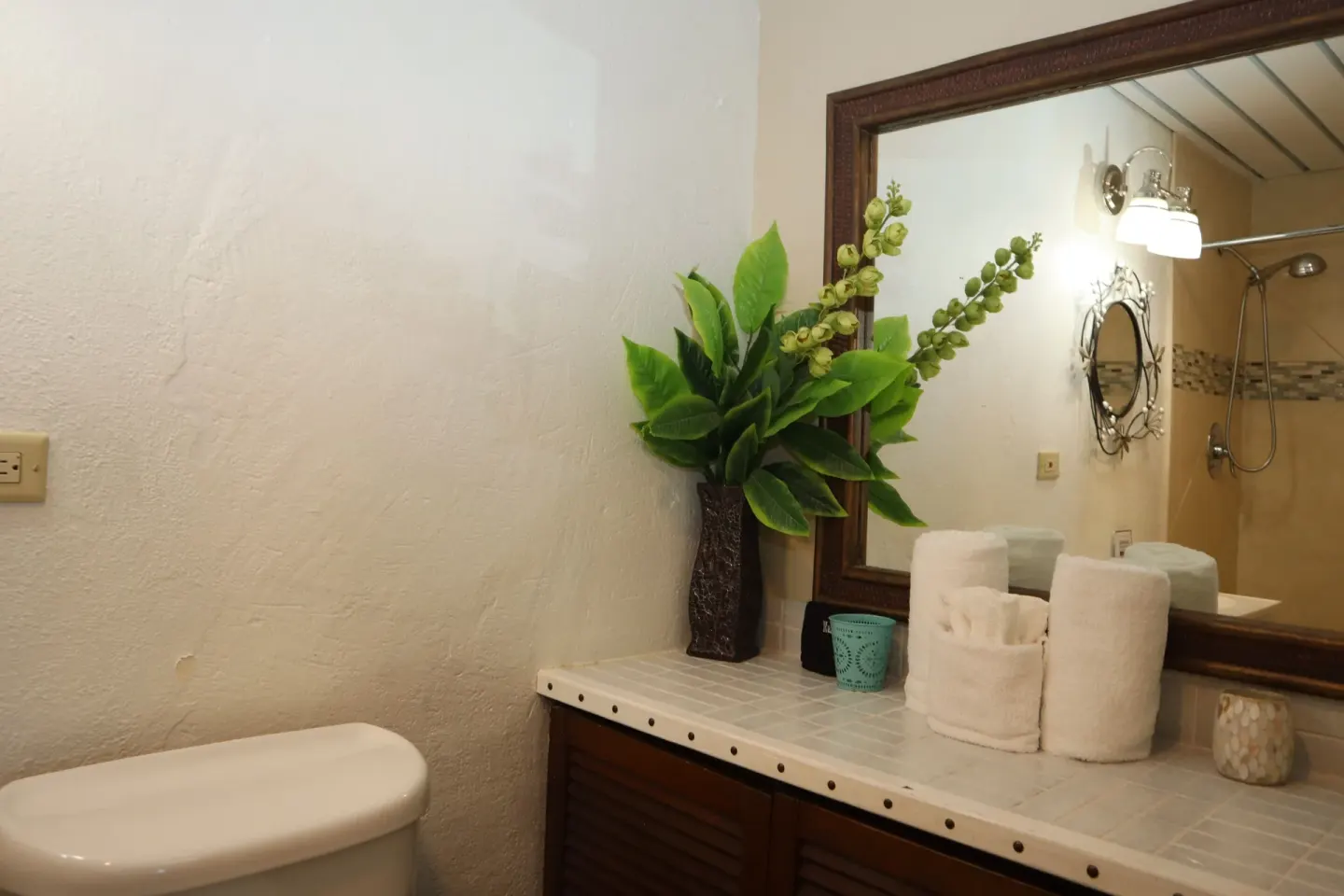 Studio bathroom vanity with mirror, towels, and decorative greenery at Point Pleasant Resort.