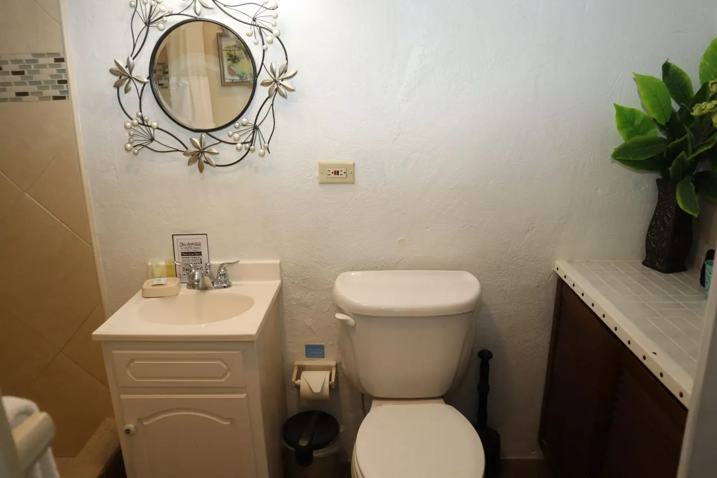 Studio bathroom with sink vanity, toilet, and round wall mirror at Point Pleasant Resort.