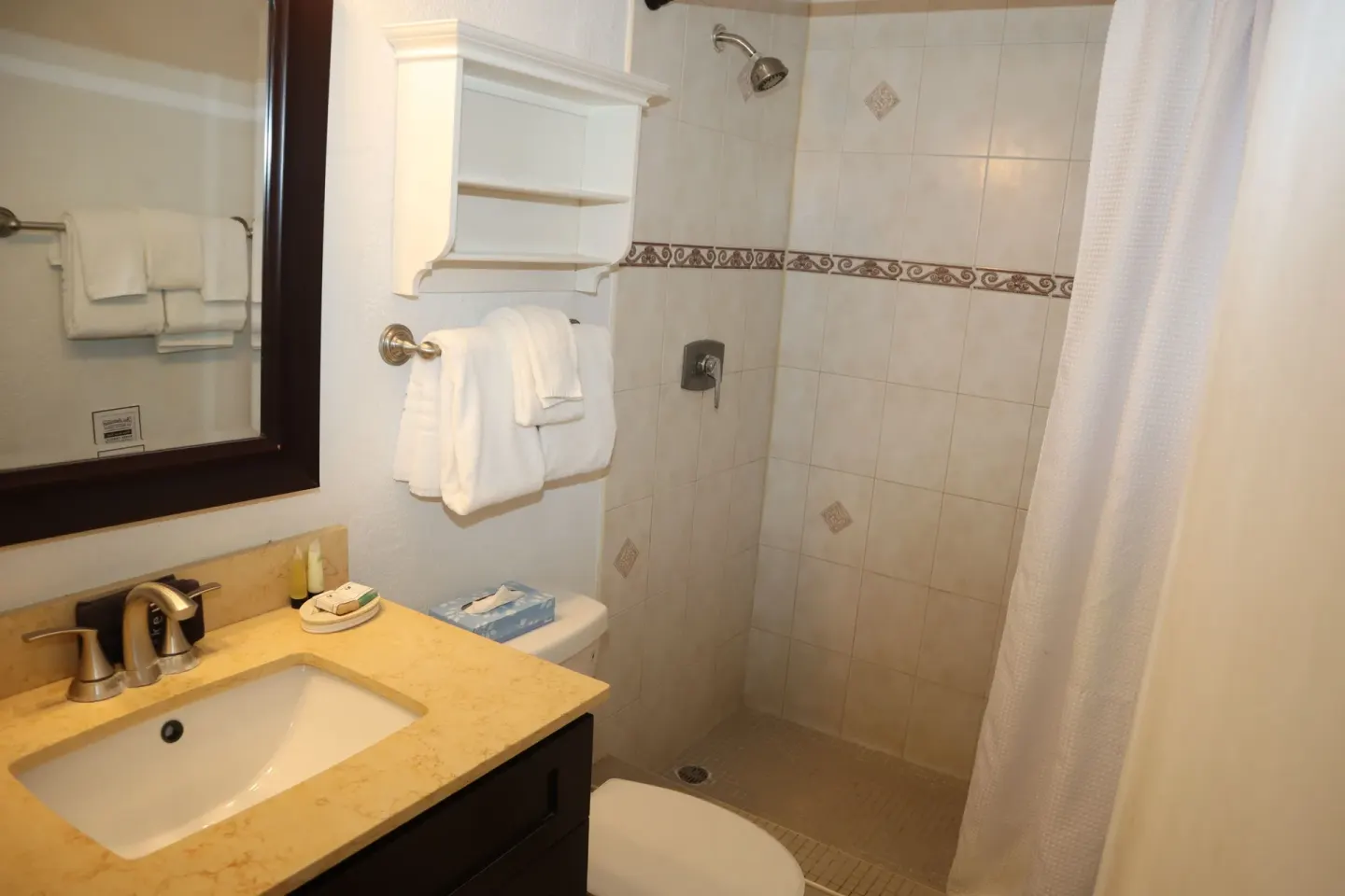 Studio bathroom with vanity, towels, and tiled walk-in shower at Point Pleasant Resort.