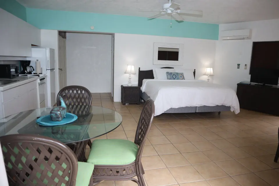 Studio with bed, kitchenette, glass dining table, and TV at Point Pleasant Resort.