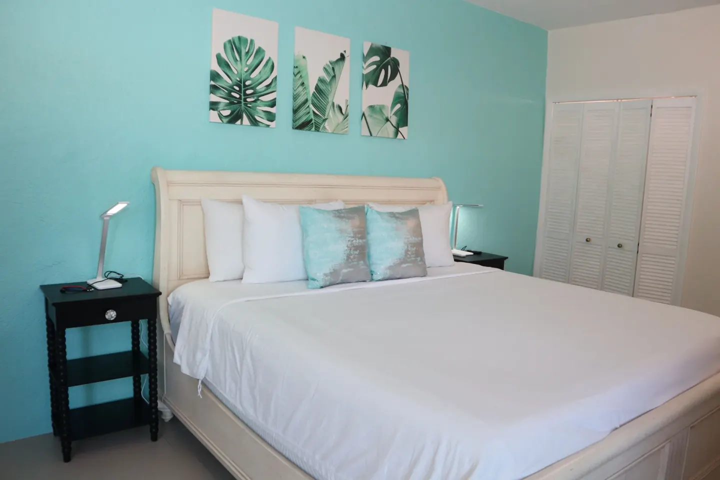 Studio bedroom with white bed, closet doors, and turquoise wall at Point Pleasant Resort.