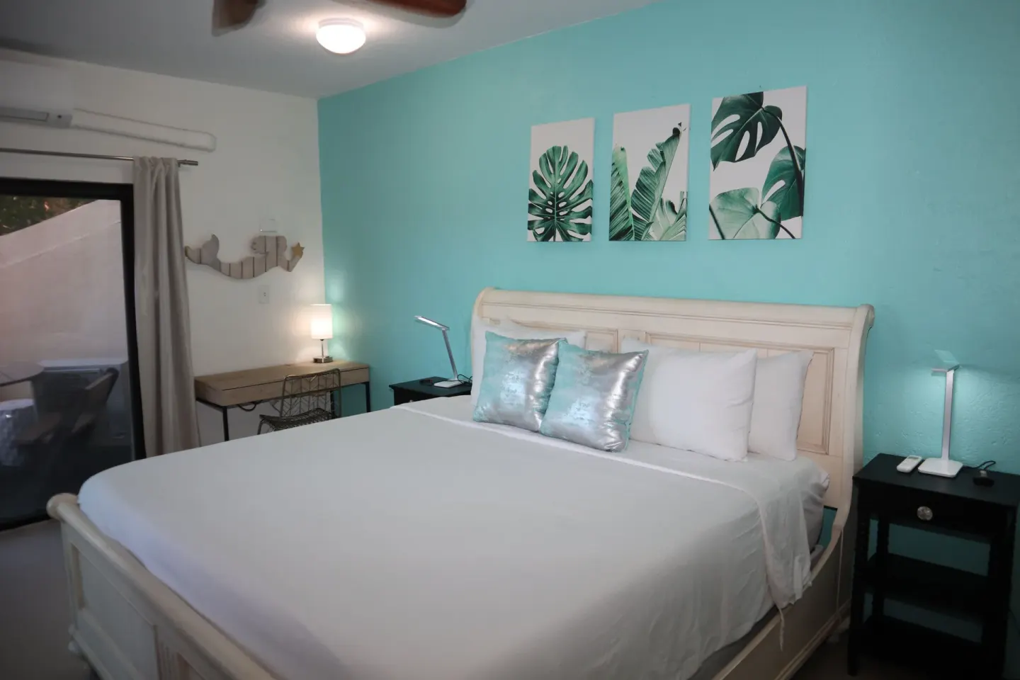 Studio bedroom with white bed, leaf art, and bedside lamps at Point Pleasant Resort.