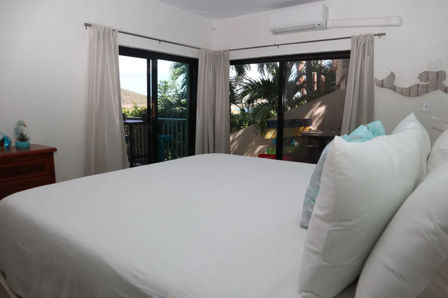 Studio bed beside sliding glass doors and curtained windows at Point Pleasant Resort.