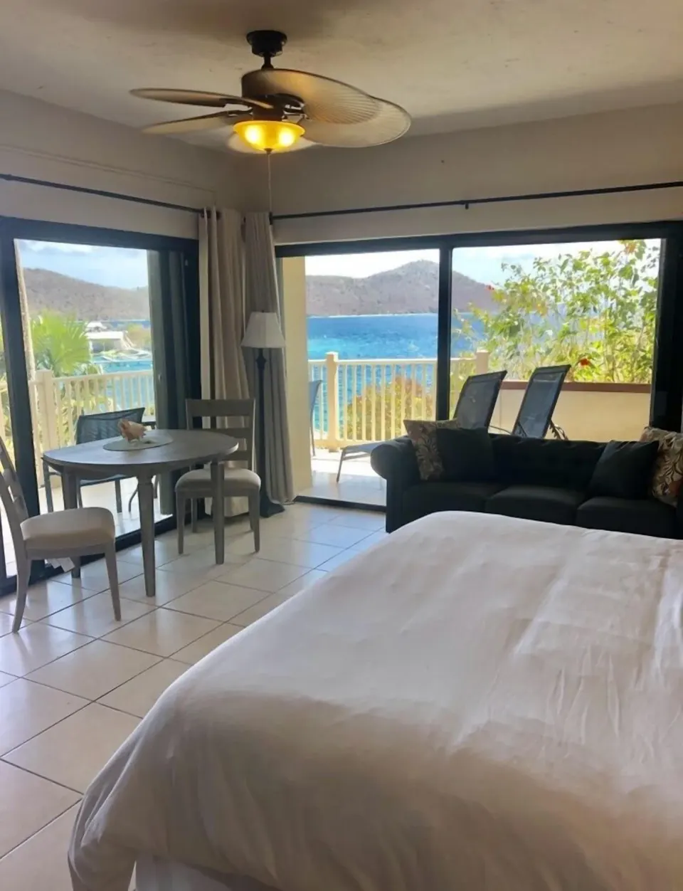 Studio room at Point Pleasant Resort with bed, sofa, dining table, and balcony water view.