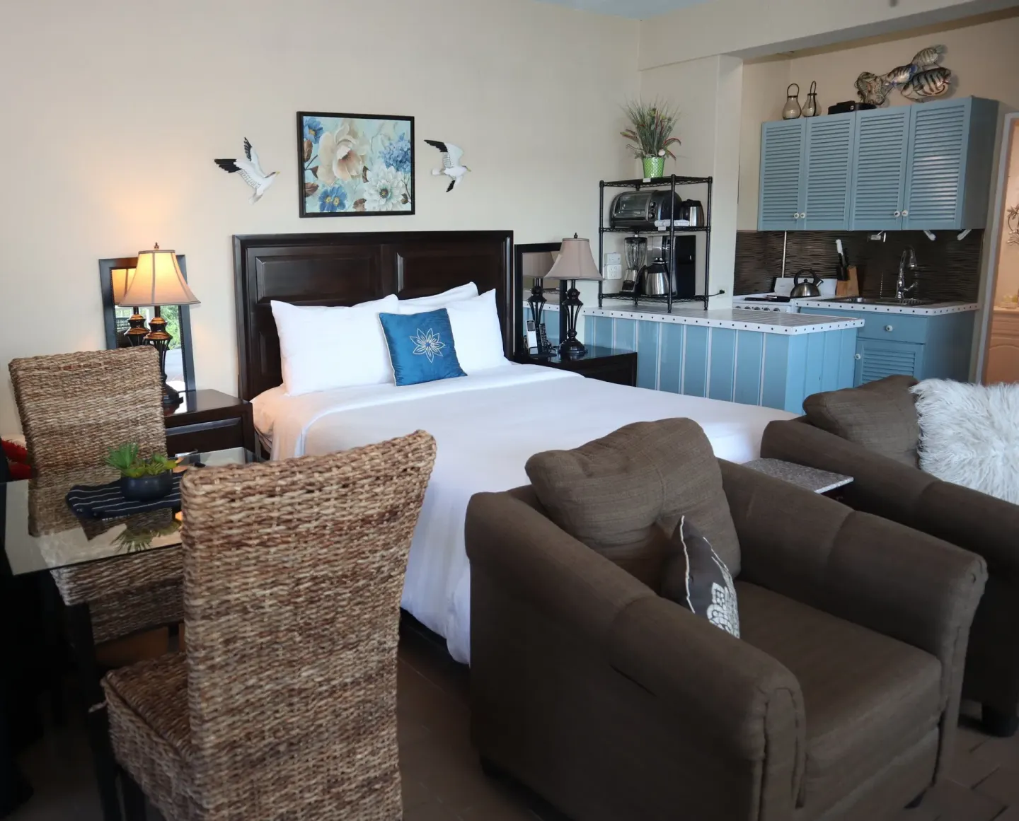 Studio king bed beside blue kitchenette and seating area at Point Pleasant Resort.