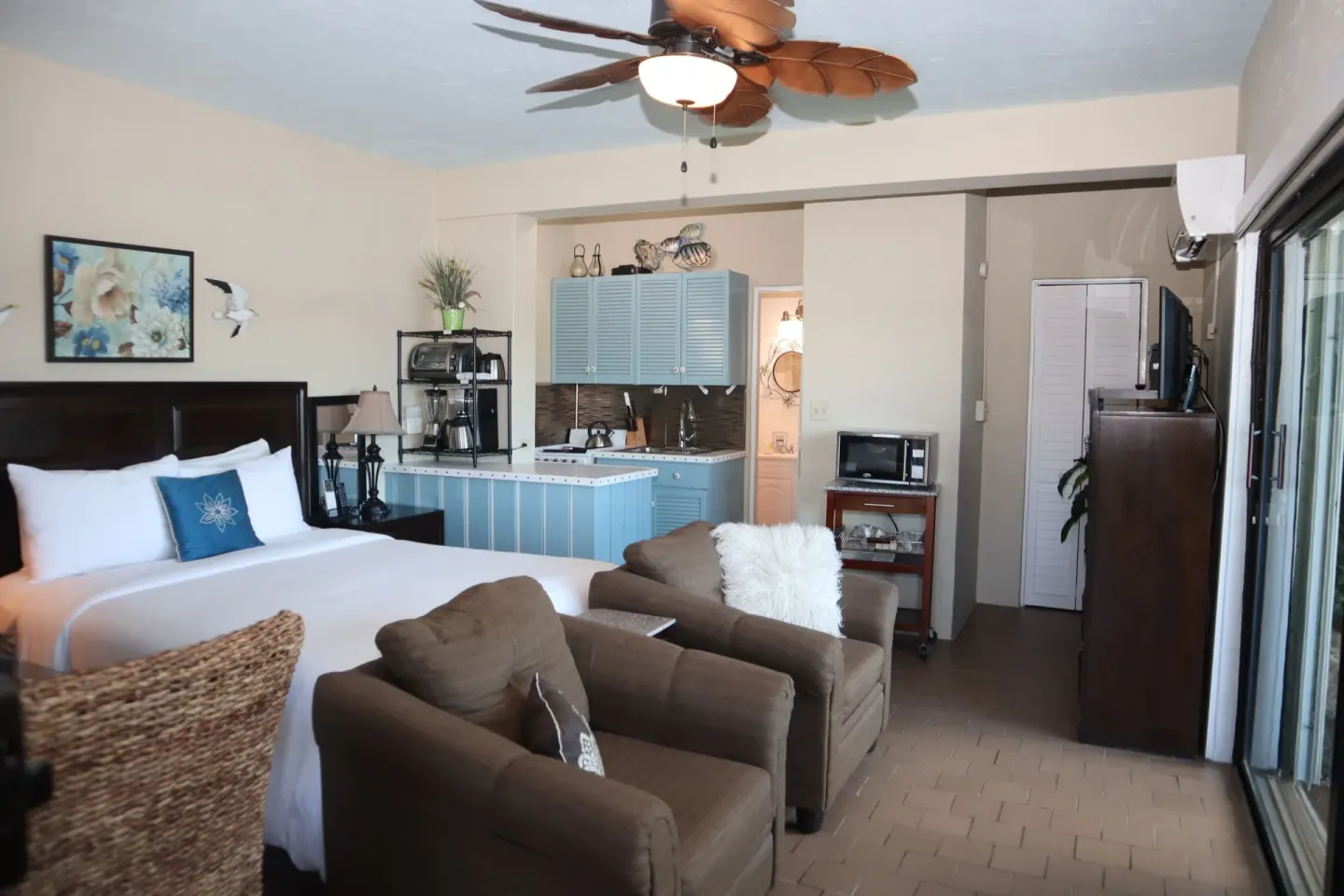 Studio king bed, lounge chairs, kitchenette, and sliding doors at Point Pleasant Resort.