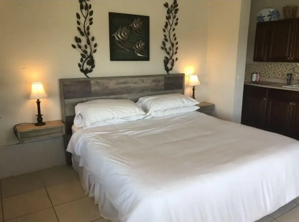 Studio at Point Pleasant Resort with bed, bedside lamps, and kitchenette visible.