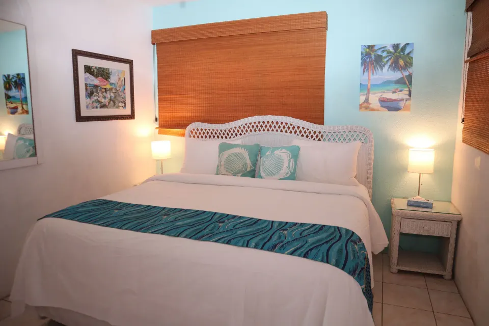 Studio king bed with white linens and turquoise accents at Point Pleasant Resort.