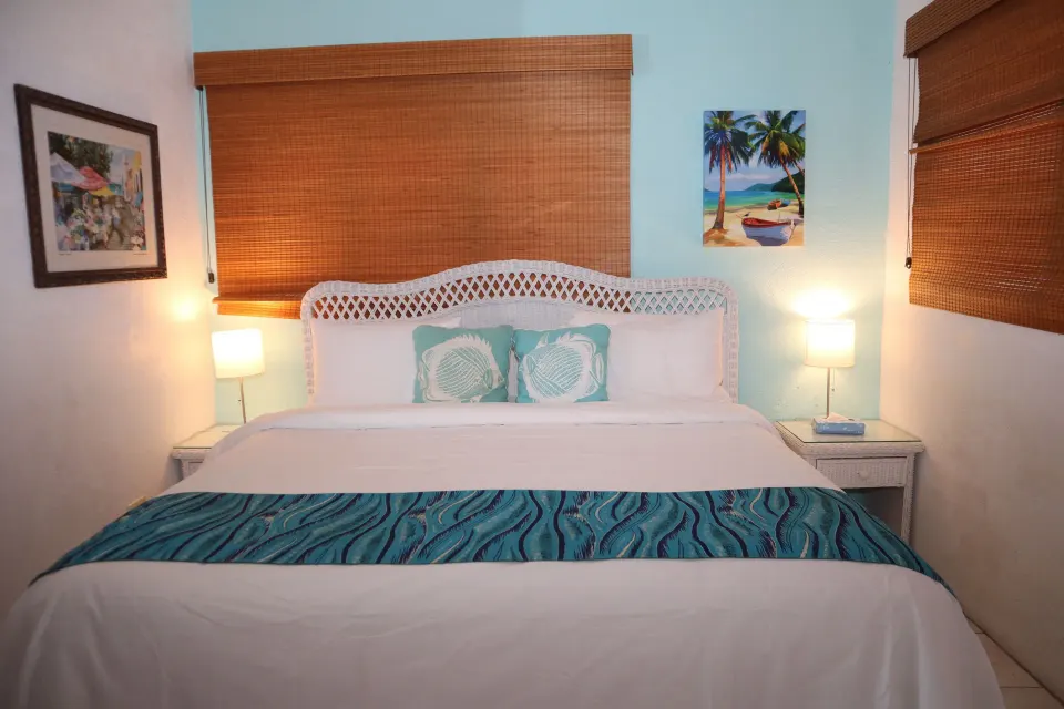 Studio king bed with wicker headboard and bedside lamps at Point Pleasant Resort.