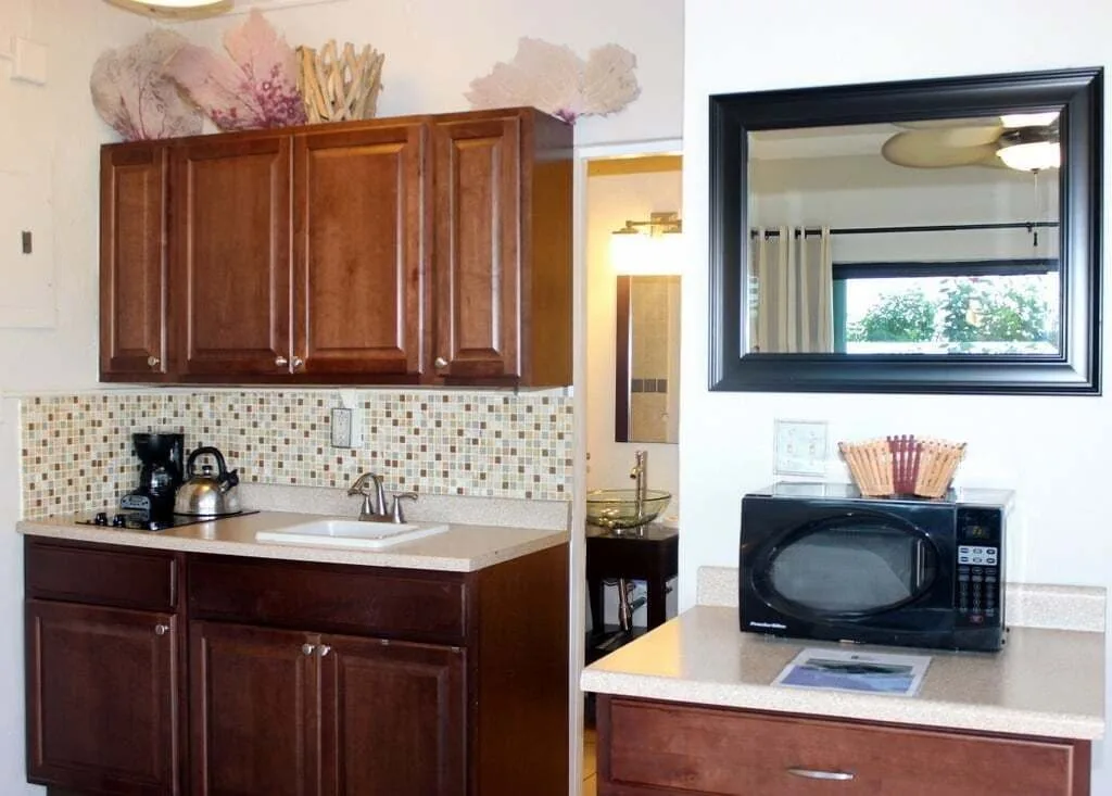 Studio kitchenette at Point Pleasant Resort with cabinets, sink, microwave, and bathroom doorway.