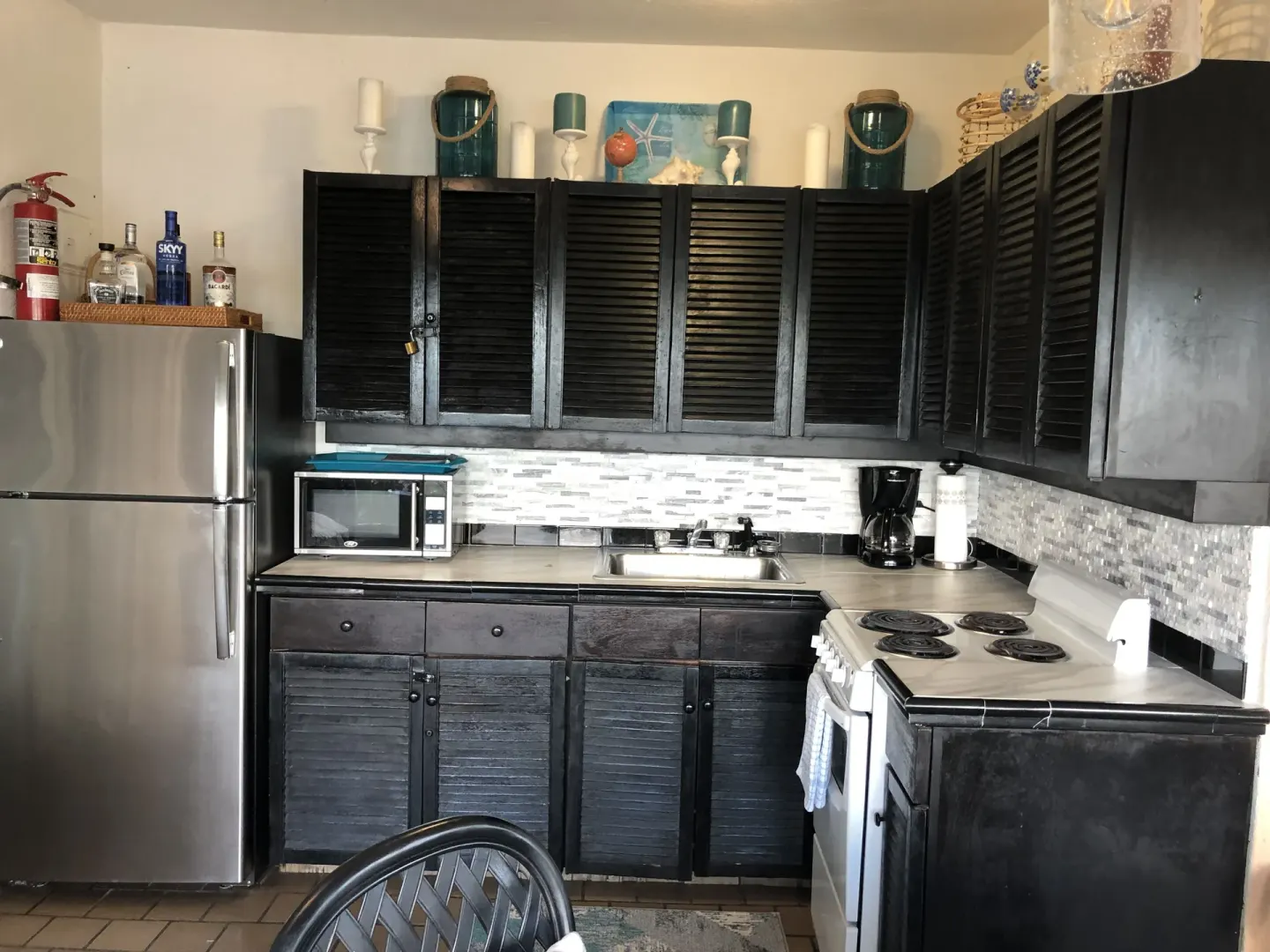 Studio kitchenette with refrigerator, stove, sink, and dark cabinets at Point Pleasant Resort.
