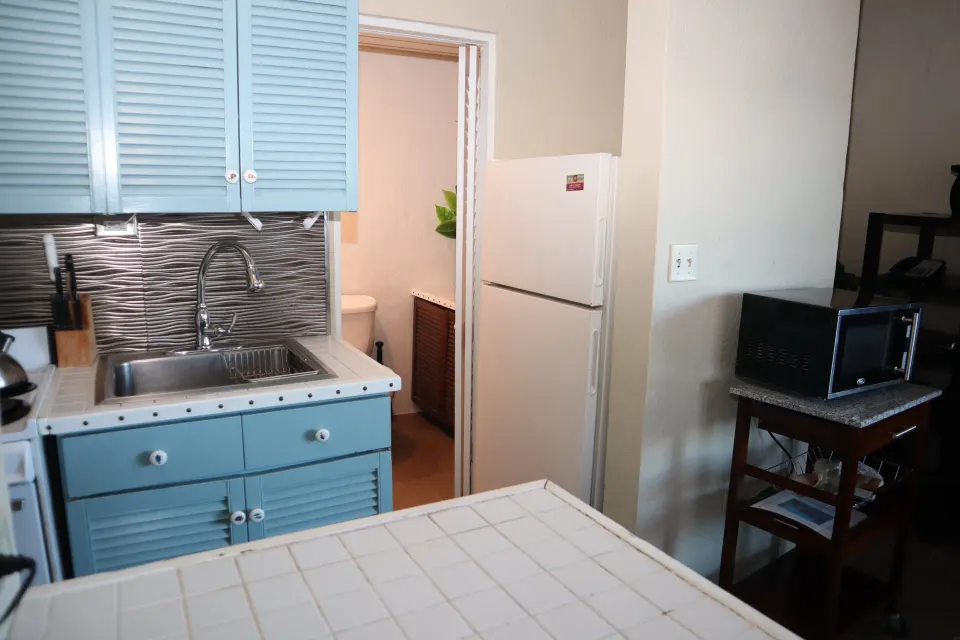 Studio kitchenette with blue cabinets, sink, refrigerator, and microwave at Point Pleasant Resort.