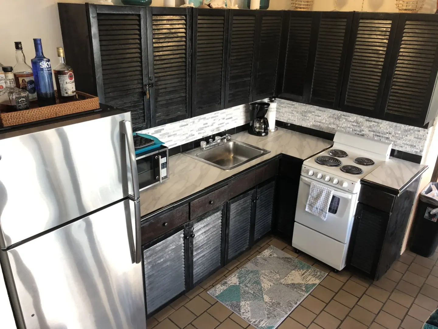 Studio kitchenette with refrigerator, sink, stove, and coffee maker at Point Pleasant Resort.