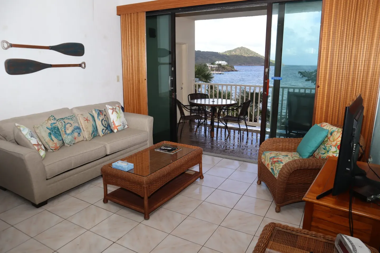 Studio living area with sofa, wicker chair, and balcony view at Point Pleasant Resort.