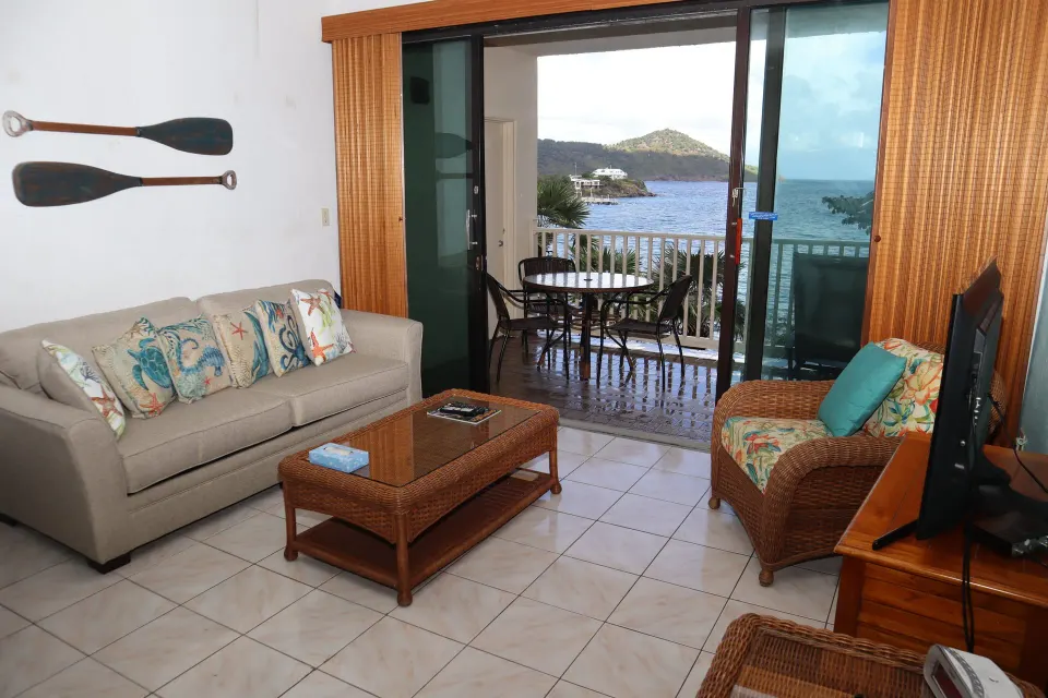 Studio living area with sofa, wicker chair, and balcony view at Point Pleasant Resort.