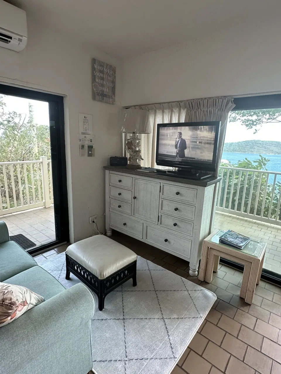 Studio living area with sofa, TV dresser, and balcony doors at Point Pleasant Resort.