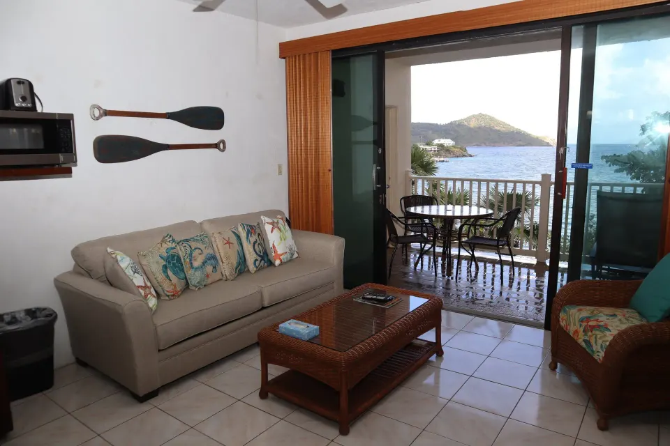 Studio living area with sofa, balcony, and water view at Point Pleasant Resort.