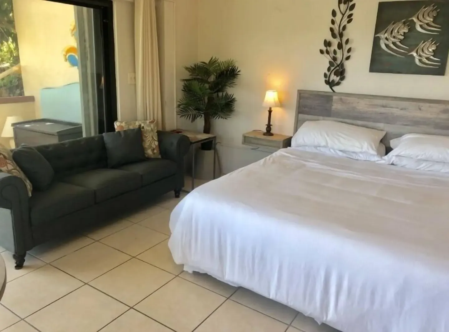 Studio room with king bed, sofa, wall art, and sliding door at Point Pleasant Resort.
