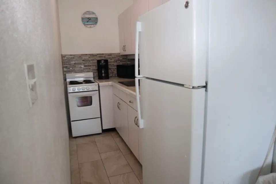 Studio kitchen with refrigerator, stove, coffee maker, and cabinets at Point Pleasant Resort.