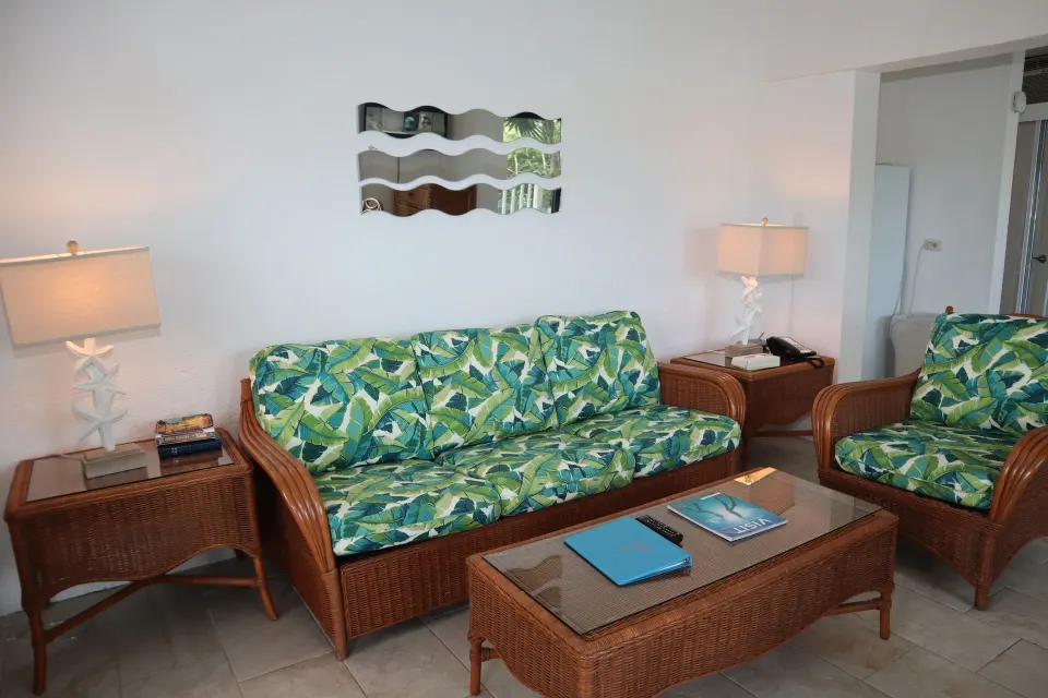 Studio sitting area with wicker sofa, armchair, lamps, and coffee table at Point Pleasant Resort.