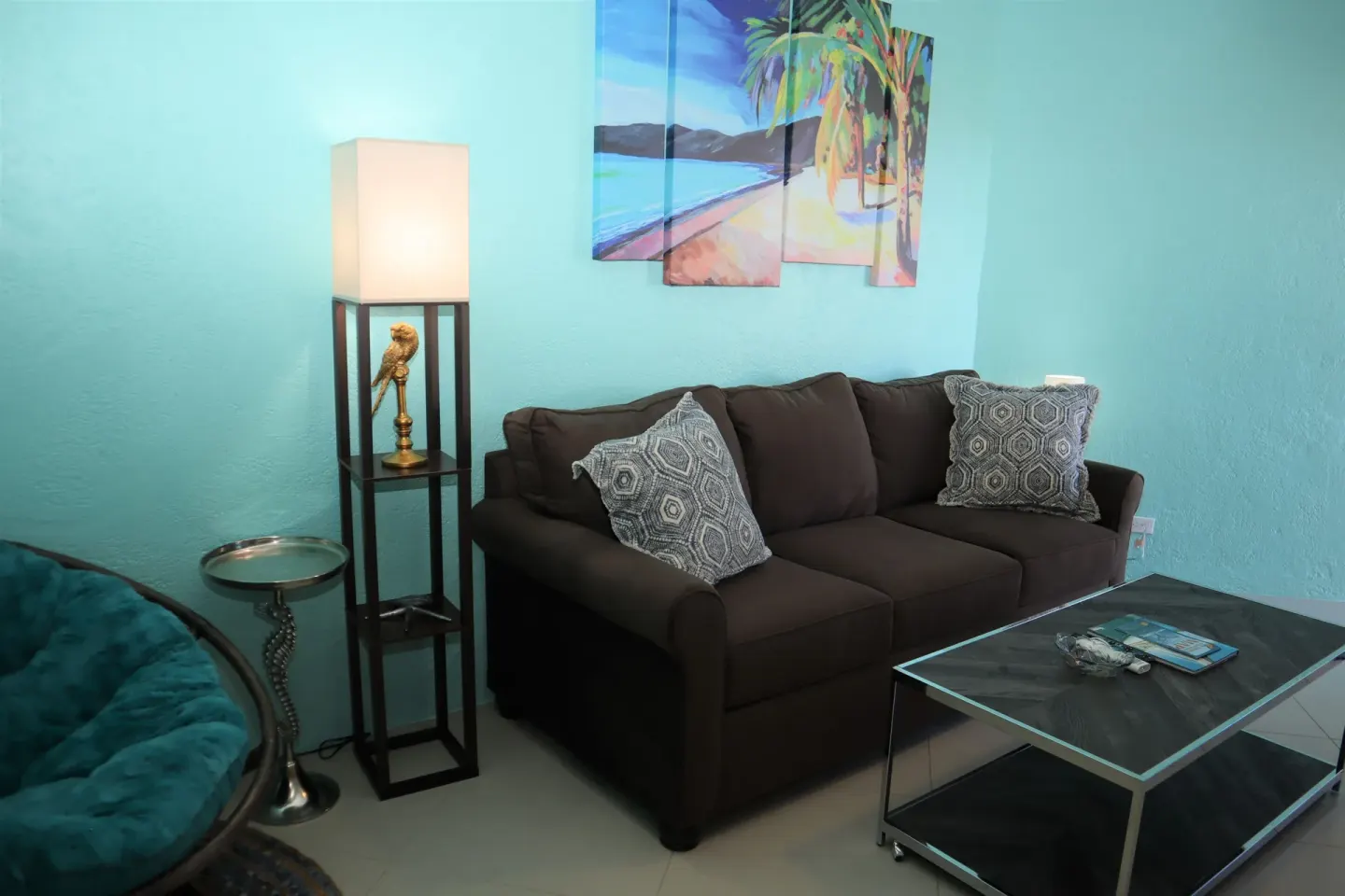 Studio sitting area with sofa, lamp, beach art, and coffee table at Point Pleasant Resort.