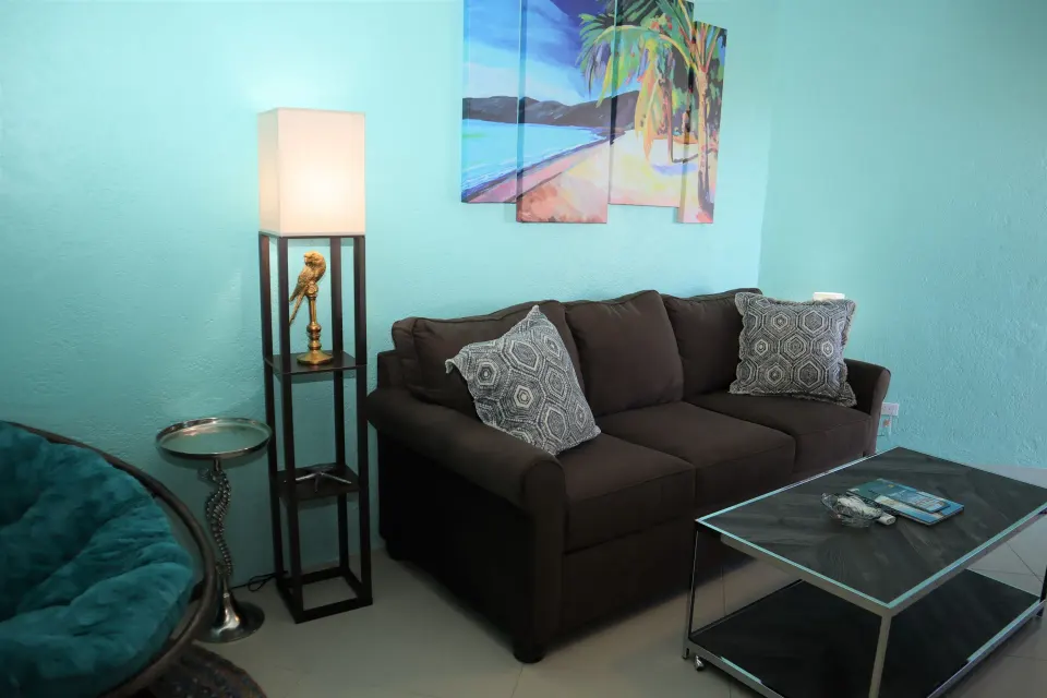 Studio sitting area with sofa, lamp, beach art, and coffee table at Point Pleasant Resort.
