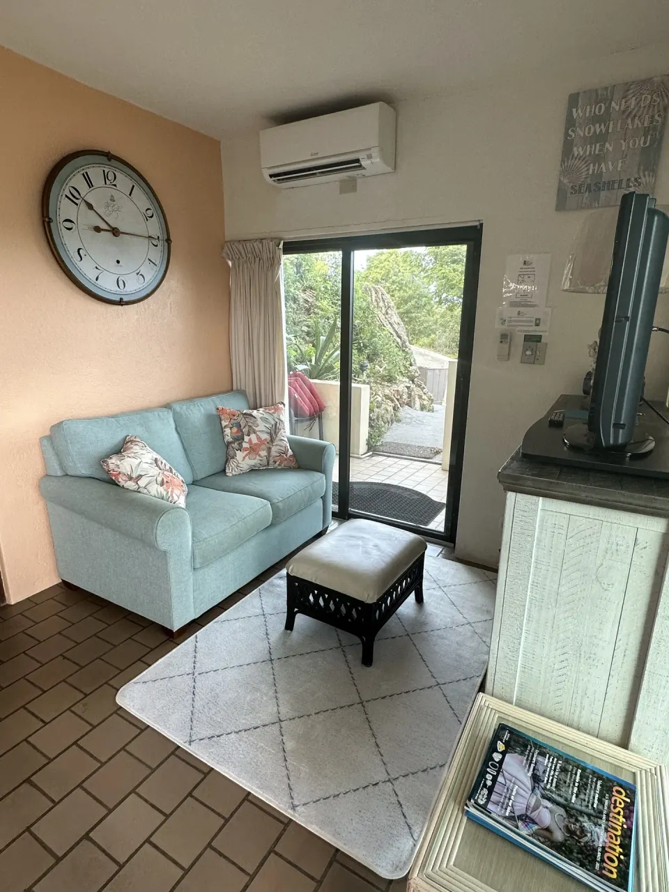 Studio sitting area with sofa, television, and patio door at Point Pleasant Resort.