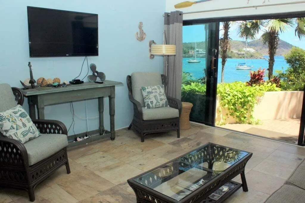 Studio sitting area with TV, glass table, and bay view at Point Pleasant Resort.