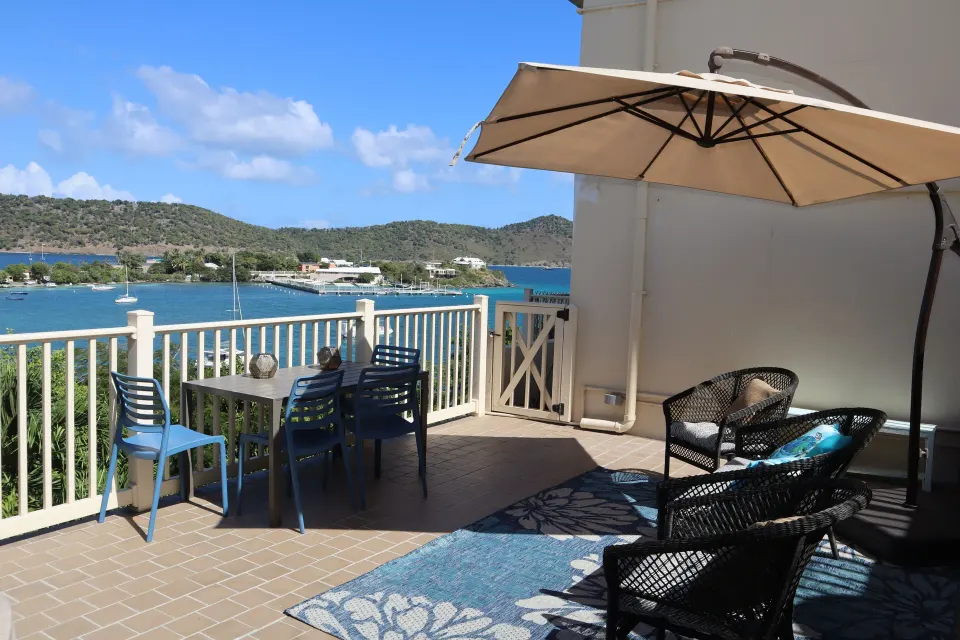 Studio terrace with dining table, lounge chairs, umbrella, and bay view at Point Pleasant Resort.