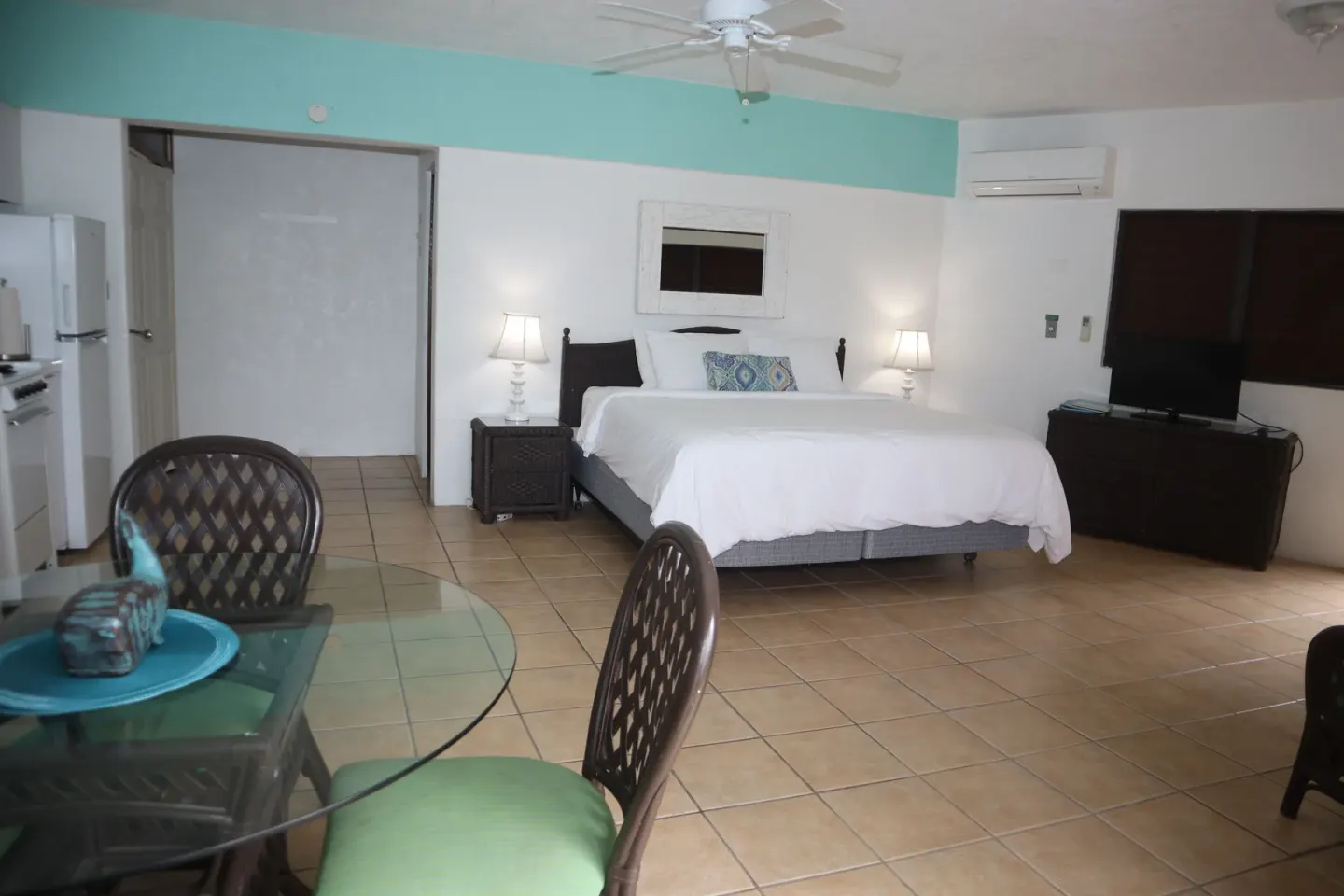 Studio with white bed, dining table, kitchenette, and TV at Point Pleasant Resort.