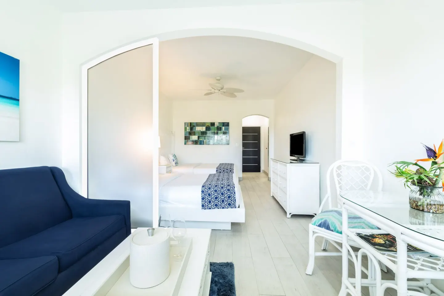 Guest room with blue sofa, glass dining table, and king bed at Ports of Call Resort.