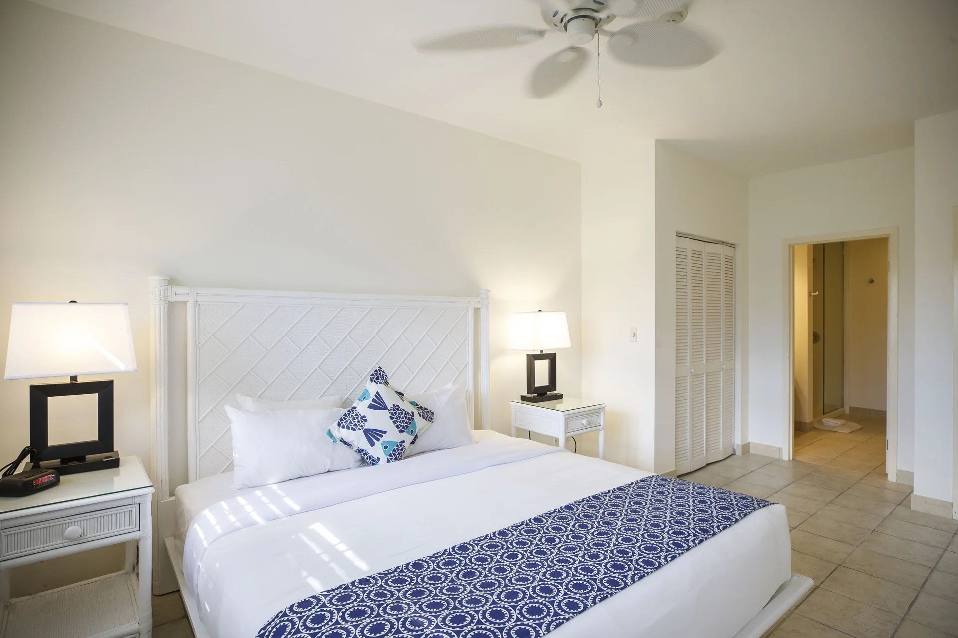 King bed guest room with white furnishings and bathroom doorway at Ports of Call Resort.