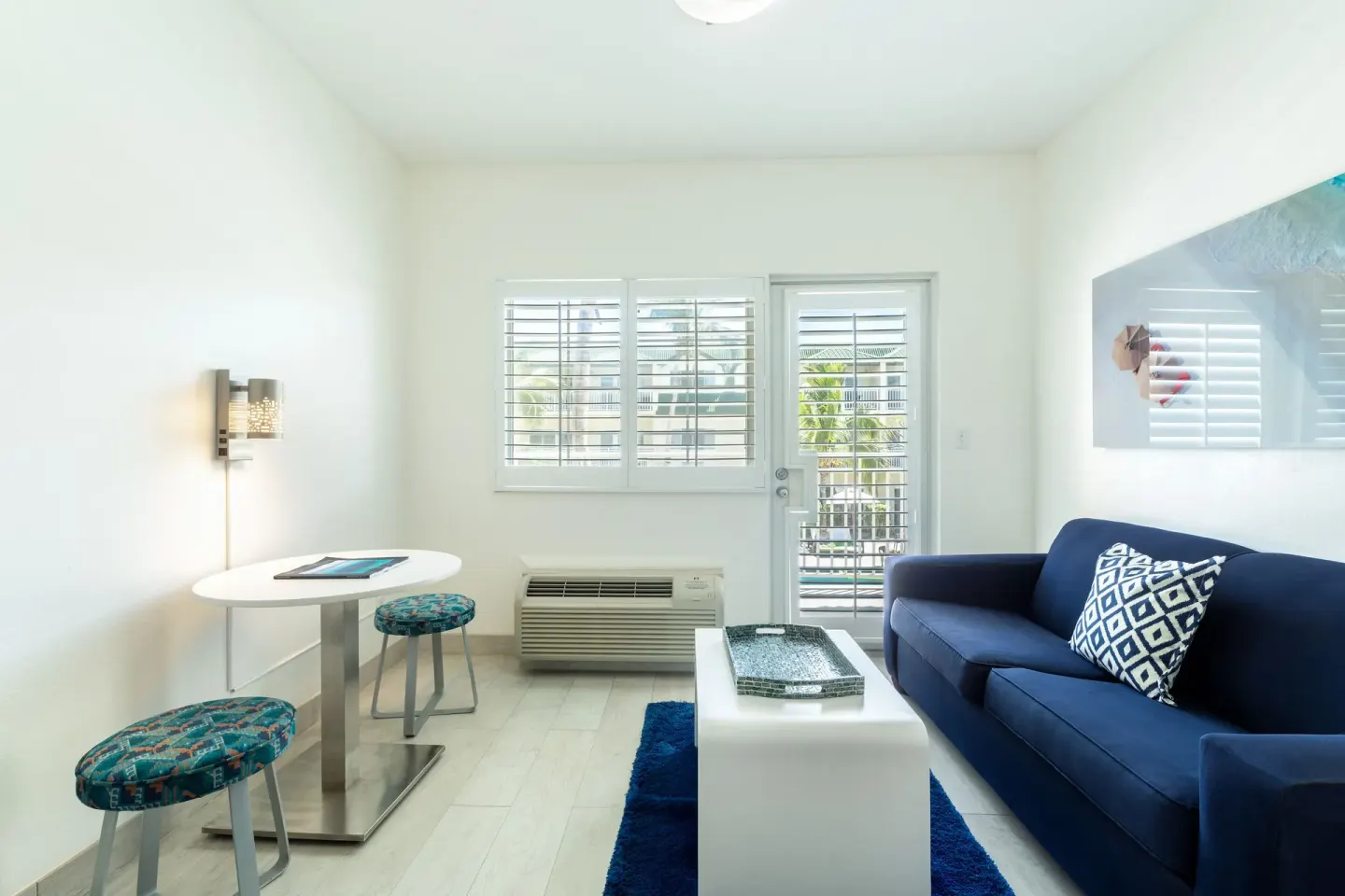 Guest room lounge with blue sofa, white table, and shutters at Ports of Call Resort.