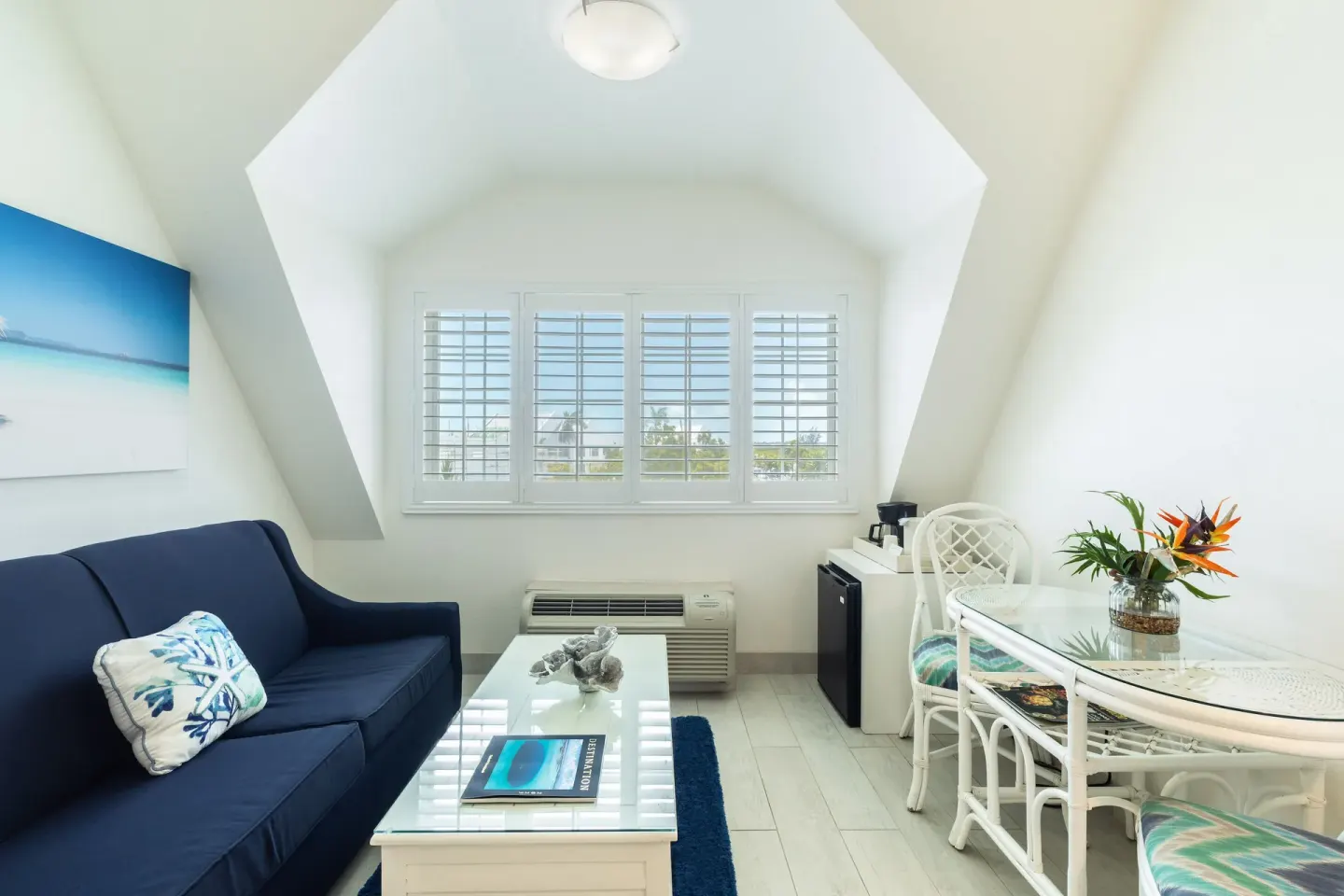 Windowed sitting area with sofa and dining table in a guest room at Ports of Call Resort.