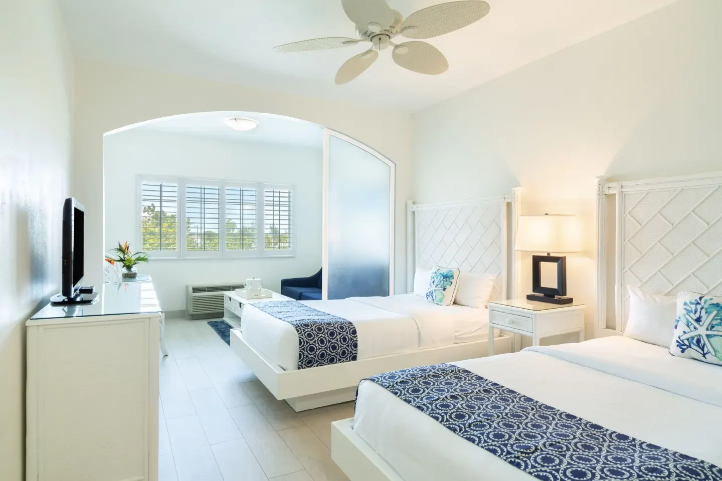 Two white beds and a sitting area in a guest room at Ports of Call Resort.