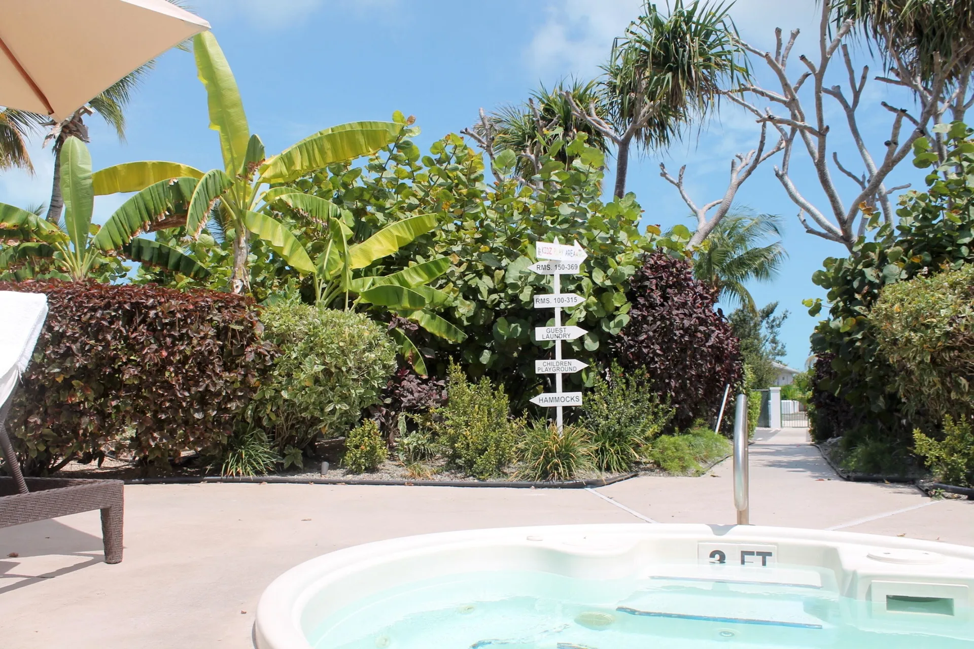 Hot tub edge, tropical landscaping, and directional sign at Ports of Call Resort.