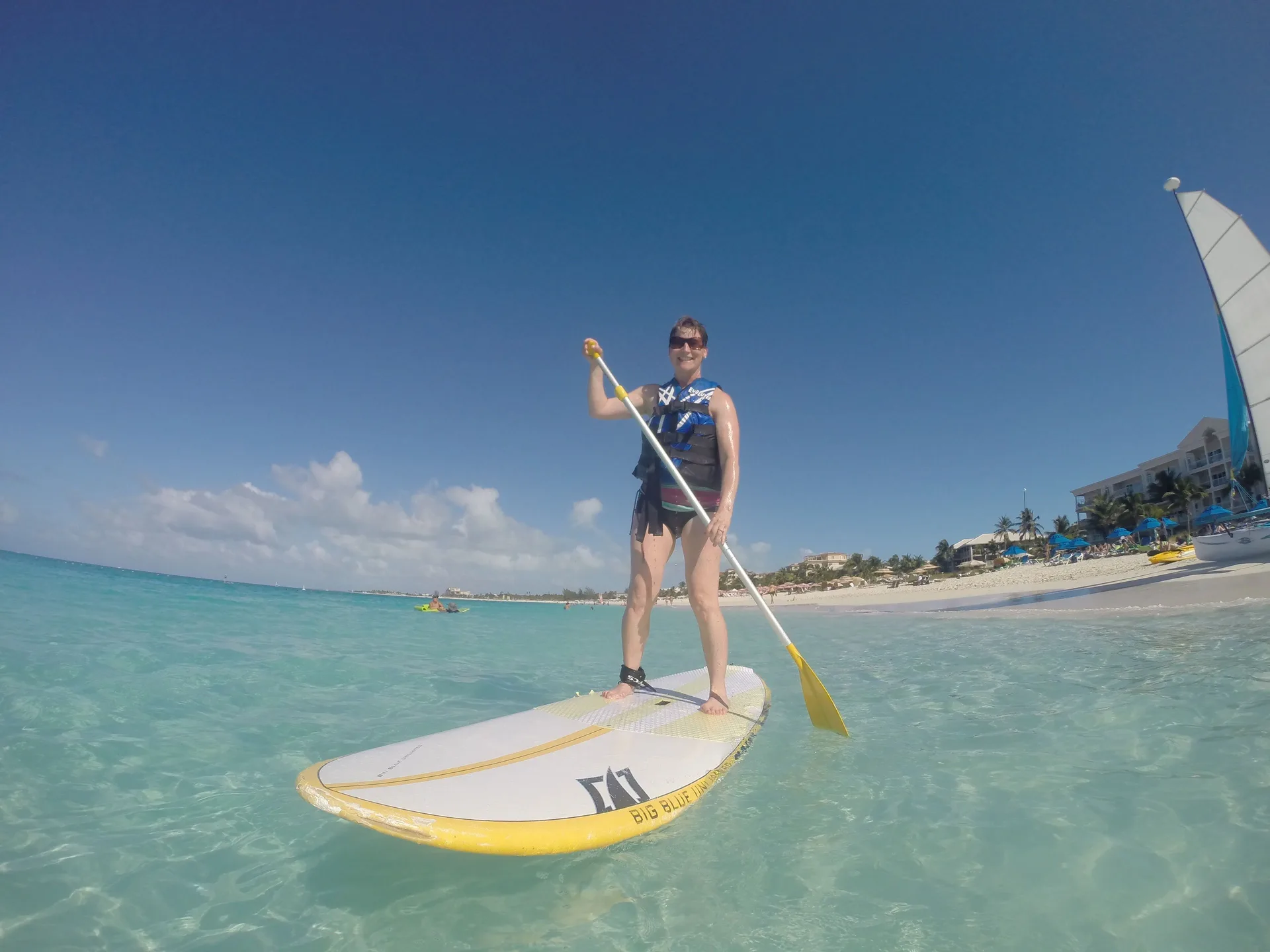 Guest paddleboarding in clear turquoise water near the beach by Ports of Call Resort.