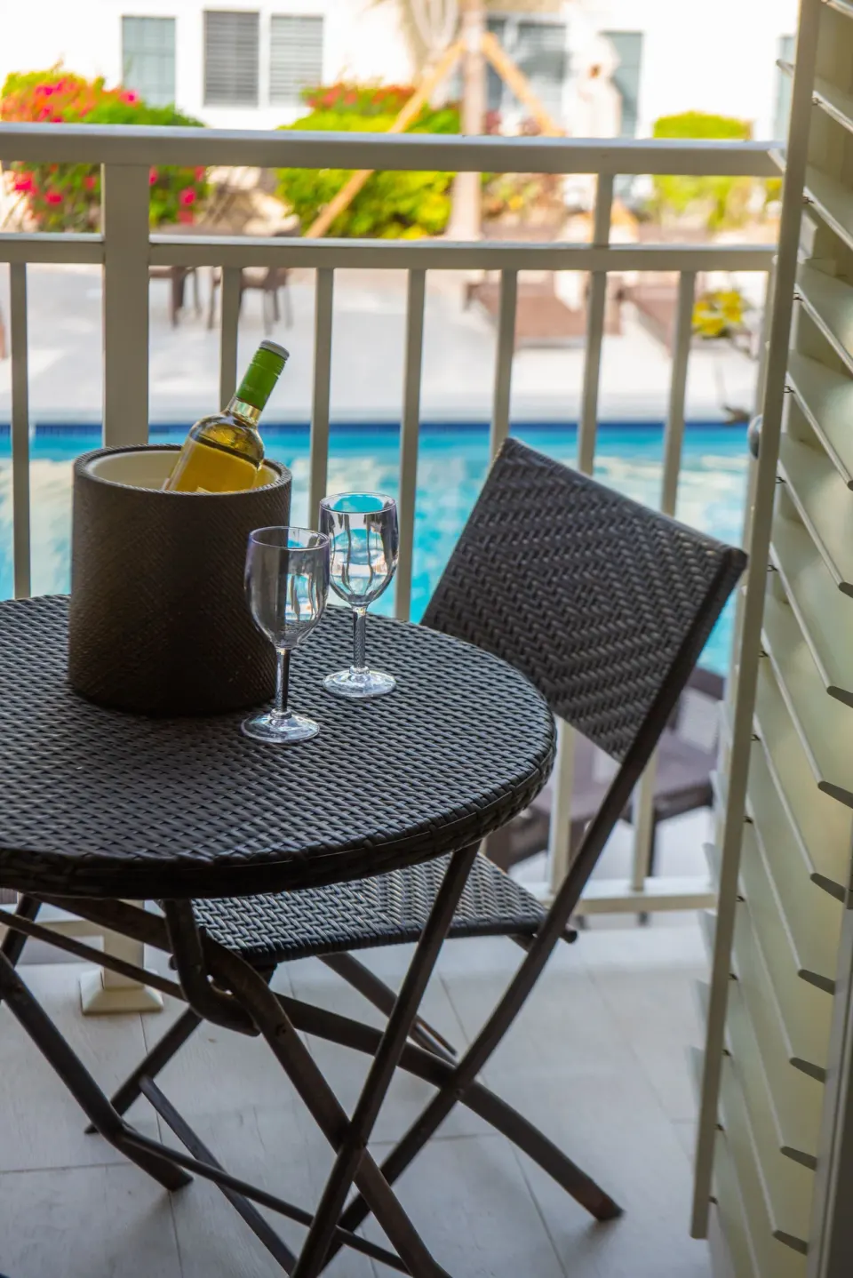 Balcony table with wine and glasses overlooking the pool at Ports of Call Resort.