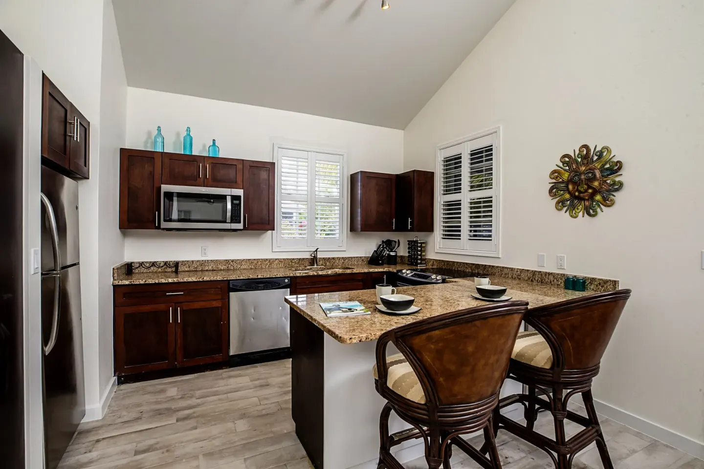 Kitchen with dark wood cabinets, island seating, and place settings at Ports of Call Resort.