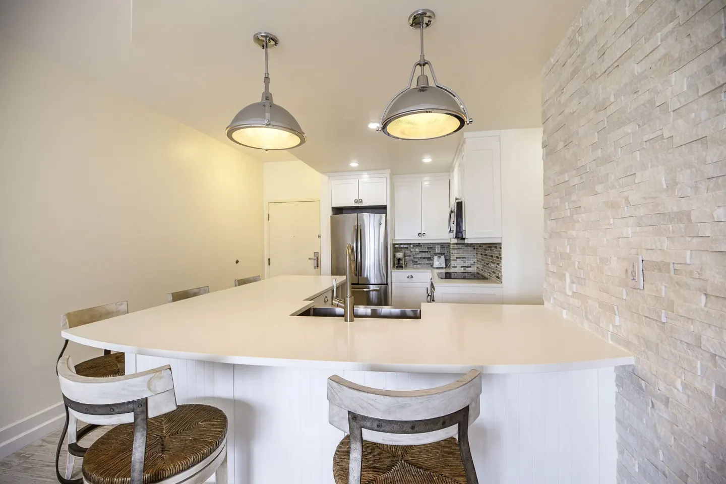 Kitchen island with stools, pendant lights, and stainless appliances at Ports of Call Resort.